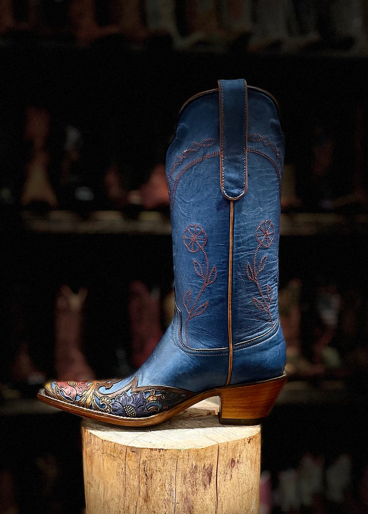Blue embroidered cowboy boot on a wooden block with a blurred background