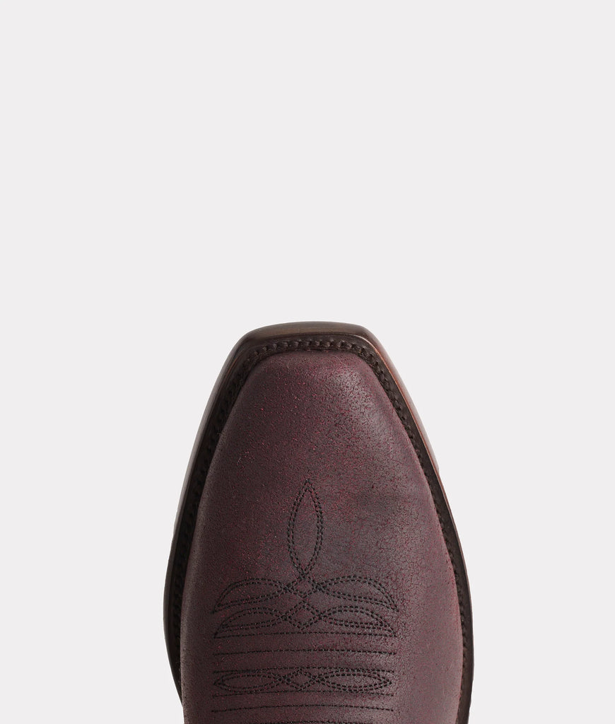 Close-up of a brown leather boot with decorative stitching on a white background