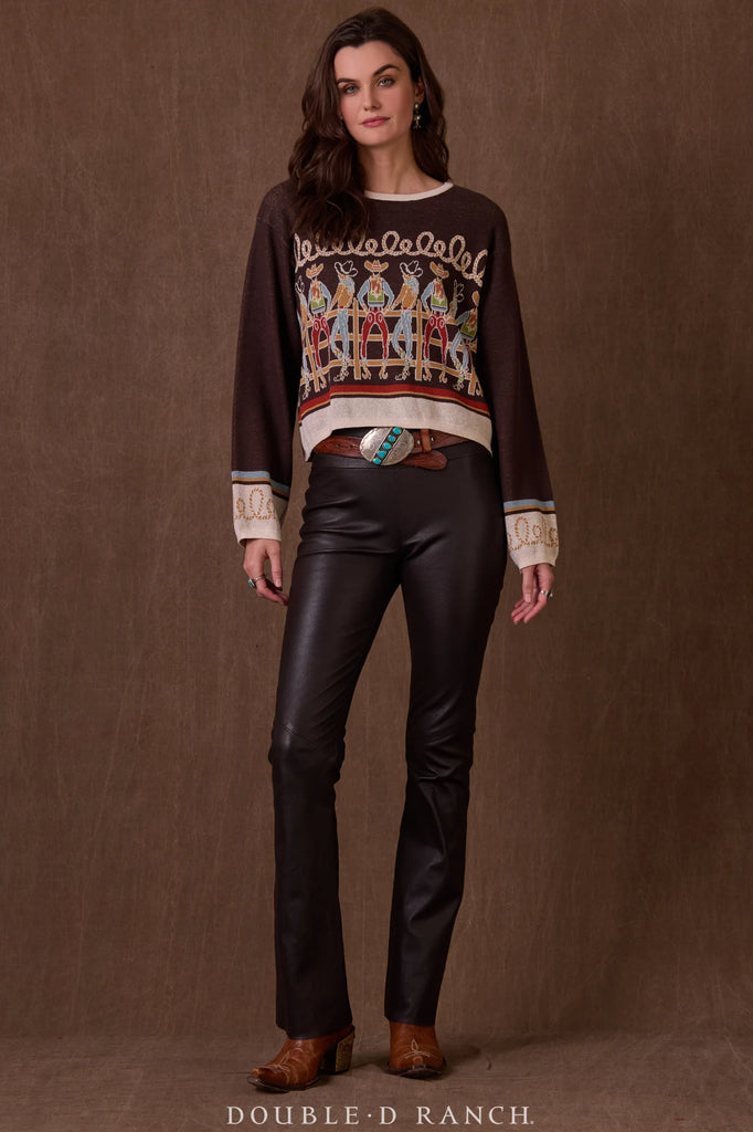 Woman wearing a patterned sweater and leather pants against a brown background
