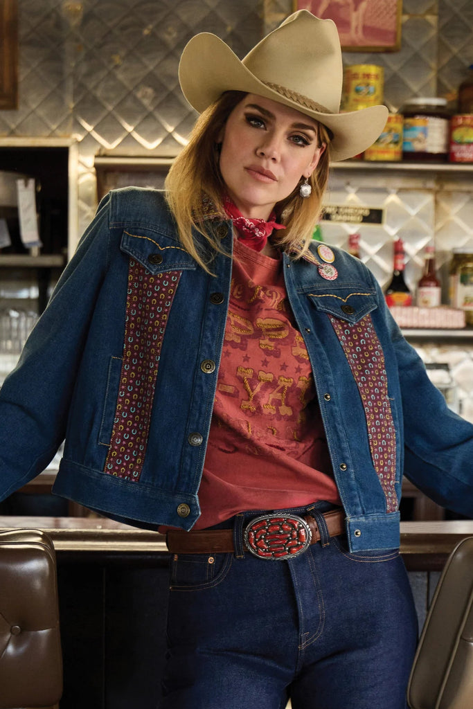 Person wearing a cowboy hat and denim jacket in a bar setting