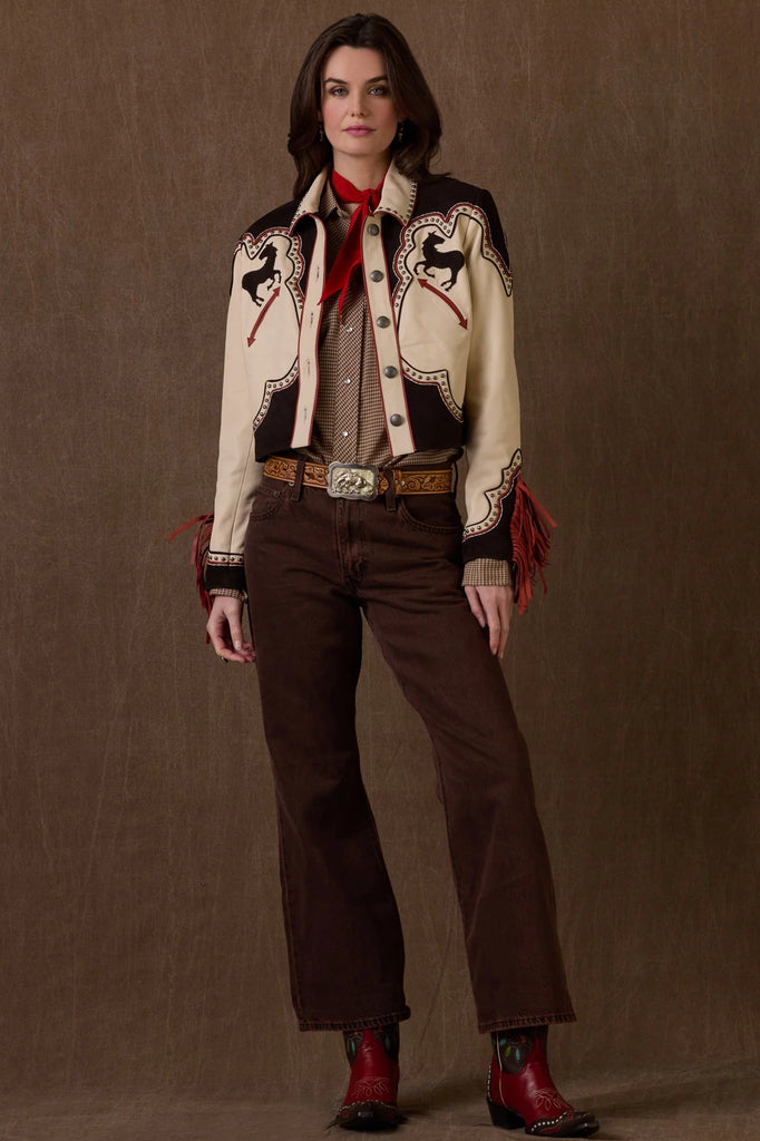 Woman wearing a western-style jacket with intricate designs on a brown background