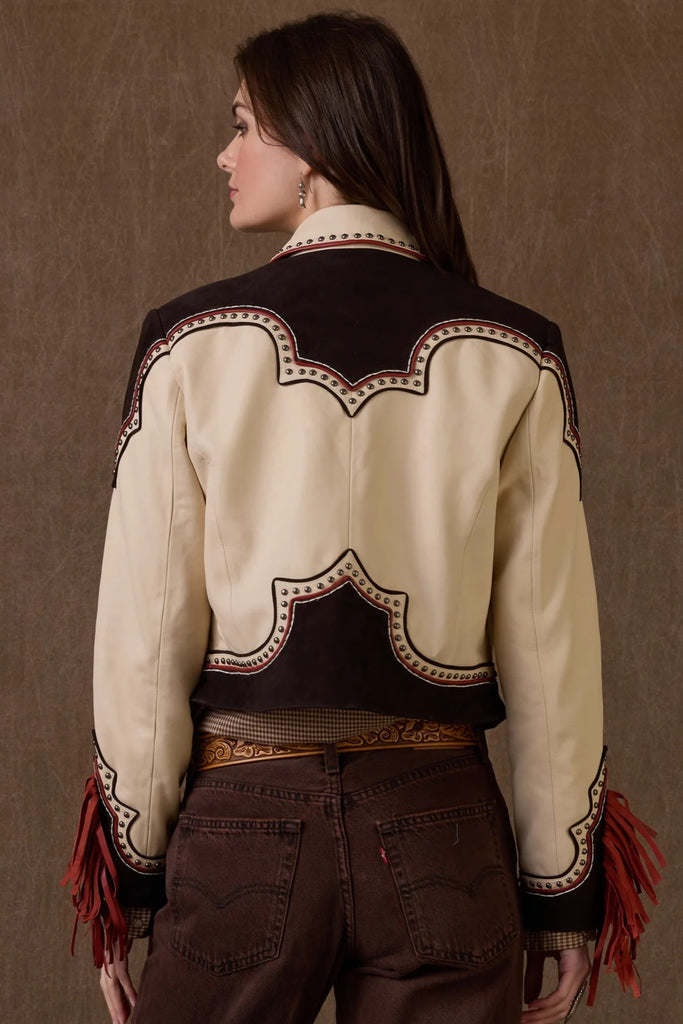 Woman wearing a cream and brown western-style jacket with intricate designs, standing against a brown background. Double-D Ranch branding visible.