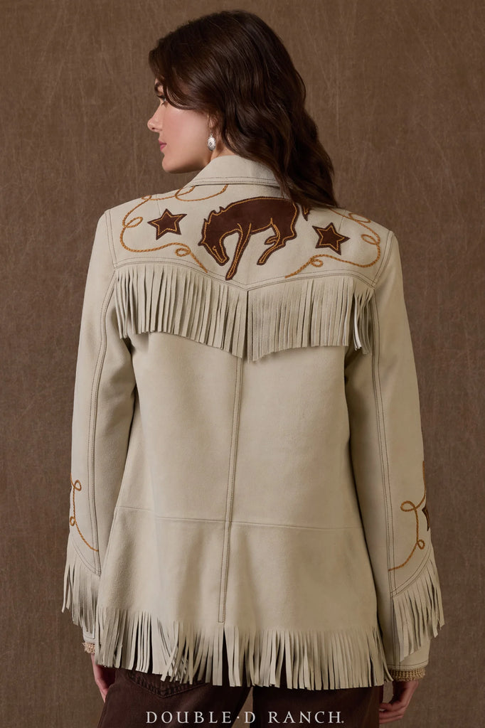 Woman wearing a beige western-style jacket with fringe and embroidery on a brown background