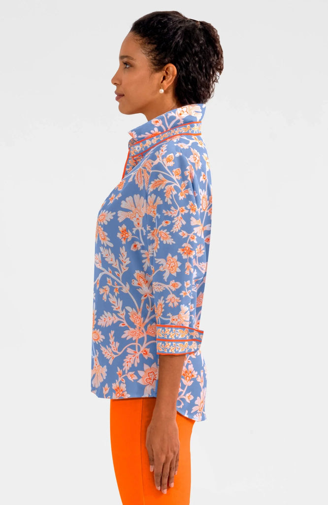 Woman wearing a blue floral blouse with orange accents on a white background