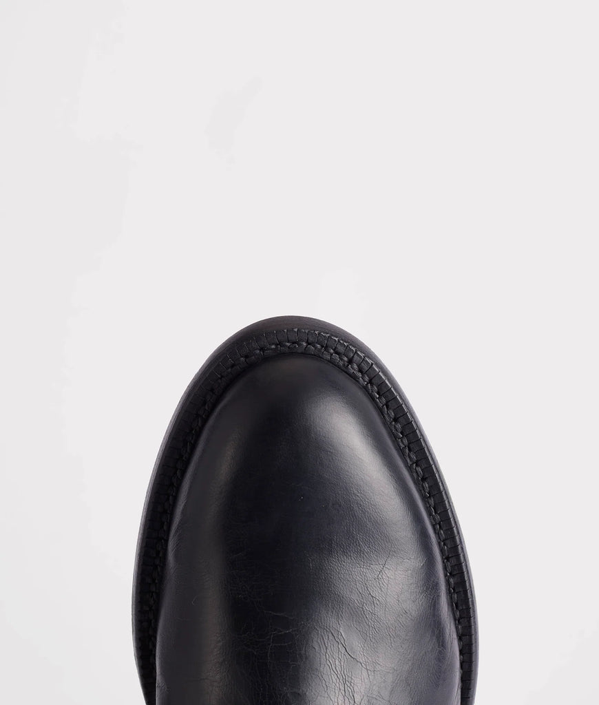 Close-up of a black leather boot sole on a light gray background
