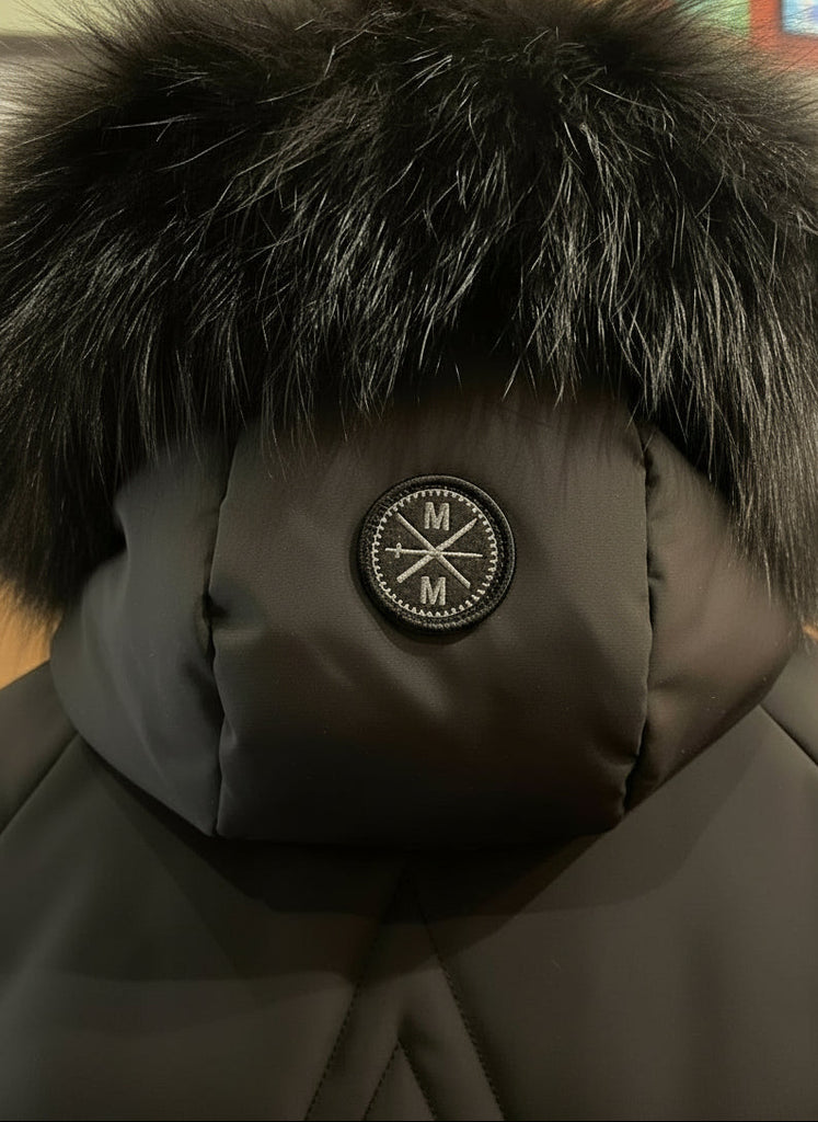 Close-up of a brown winter coat with fur hood and logo patch.