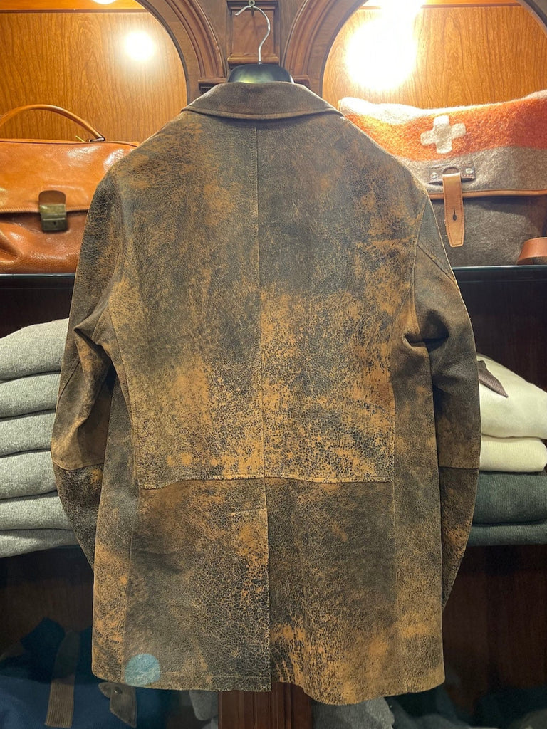 Antic leather jacket hanging on a rack with folded clothes underneath