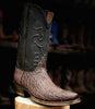 Brown cowboy boot with black leather accents on a wooden block against a dark background