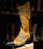Cowboy boot with intricate yellow and black design on a wooden block against a blurred background