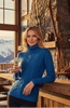 Blue cable knit turtleneck sweater on a white background