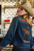 Woman wearing a blue denim jacket with cowboy graphics and text in a kitchen setting