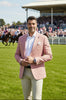 Man wearing a pink blazer over a white shirt with a dark patterned background