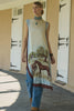 Woman wearing a long dress with horse design in front of barn doors.