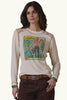Woman wearing a long-sleeve shirt with a graphic design on a brown background