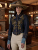 Woman wearing a dark blue embroidered jacket with gold details, beige pants, and a brown hat against a brown background.