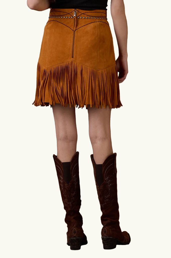 Person wearing a brown suede fringe skirt and cowboy boots on a brown background with 'Double D Ranch' branding.