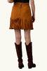 Person wearing a brown suede fringe skirt and cowboy boots on a brown background with 'Double D Ranch' branding.