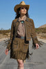 Woman in a western-style outfit with a jacket and skirt, standing on a road with a desert landscape.