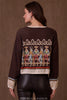 Woman wearing a brown sweater with embroidered design on a brown background