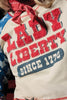 Hoodie with 'LADY LIBERTY SINCE 1876' text and a red bandana on a person.