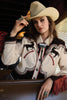 Woman wearing a western-style jacket with horse designs and a cowboy hat, sitting in a vehicle.