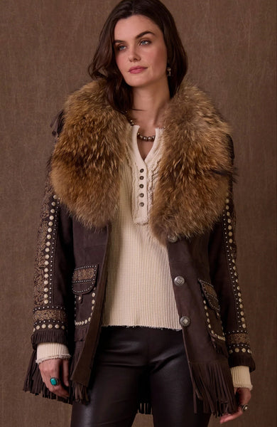 Woman wearing a brown leather jacket with fur collar and fringes on a brown background
