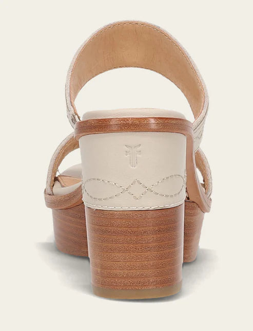 Close-up of a sandal with wooden sole and beige strap on a light background
