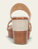 Close-up of a sandal with wooden sole and beige strap on a light background