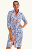 Woman wearing a blue floral dress with orange accents on a white background