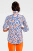 Woman wearing a blue floral blouse with orange pants on a white background