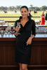 Woman wearing a black dress standing at a polo match