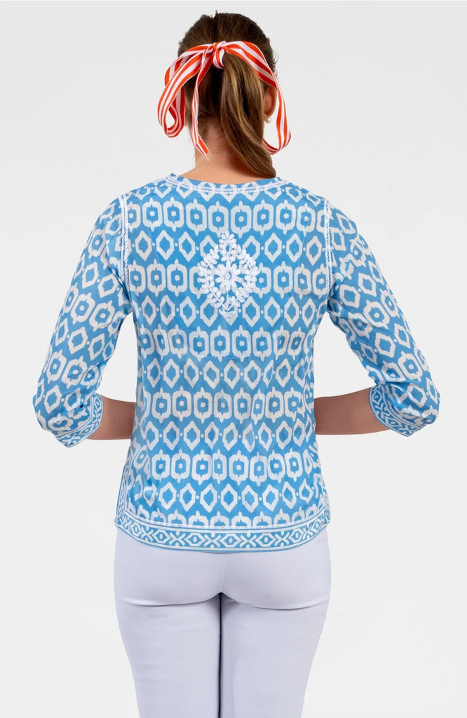 Woman wearing a blue patterned shirt with a white background