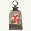 Decorative lantern with a miniature scene of a red barn and deer inside a snow globe.