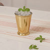 Gold mint julep cup with ice and mint leaves on a striped tablecloth.