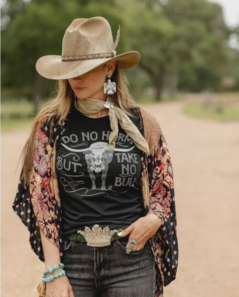 Woman wearing a cowboy hat, black t-shirt with graphic design, and floral kimono in an outdoor setting.