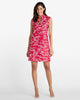 A woman modeling a sleeveless red dress with a white toile-style print, standing against a plain light gray studio background.