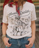 A woman wearing a white graphic t-shirt with a black cowboy and steer/bull illustration and the text 'Howdy Darlin''.
