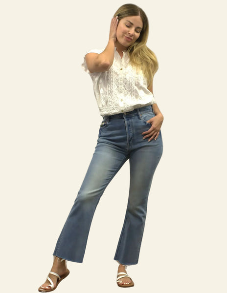 Woman wearing a white top and blue jeans on a plain background