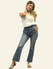 Woman wearing a white top and blue jeans on a plain background
