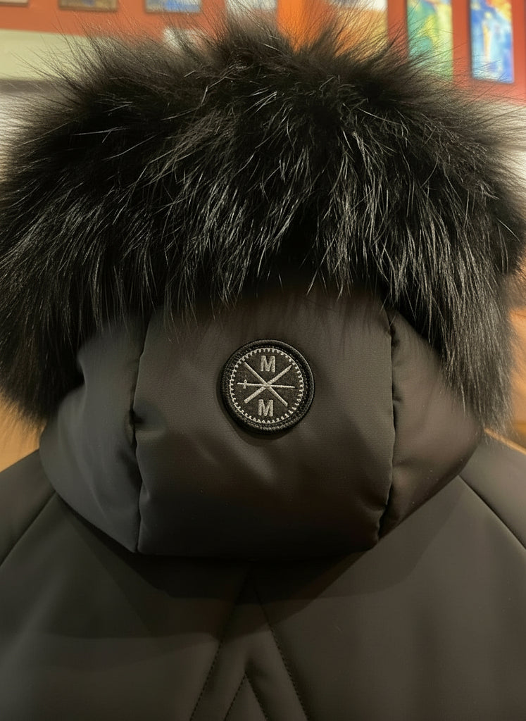 Close-up of a brown winter coat with fur hood and logo patch.