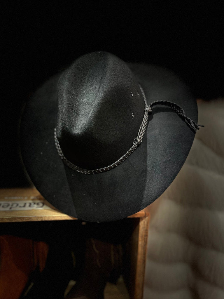 Black cowboy hat on a wooden shelf with a blurred background