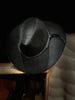 Black cowboy hat on a wooden shelf with a blurred background