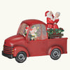 Red Christmas truck with Santa and Mrs. Claus figures on a dark background