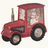 Red tractor-shaped snow globe with a snowman inside on a dark background