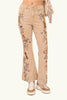 Beige jeans with floral horse and cowgirl embroidery worn by a person, with an American flag in the background.