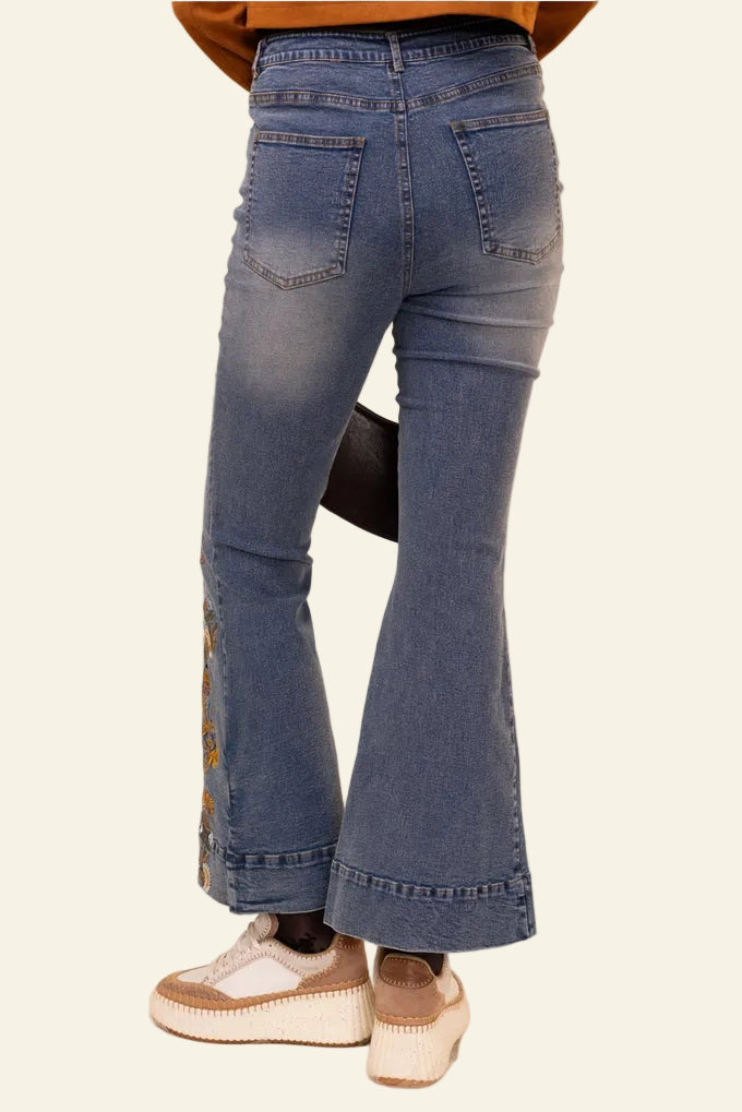 Flared jeans worn by a person on a beige background