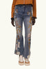 Flared jeans with floral embroidery worn by a person on a beige background
