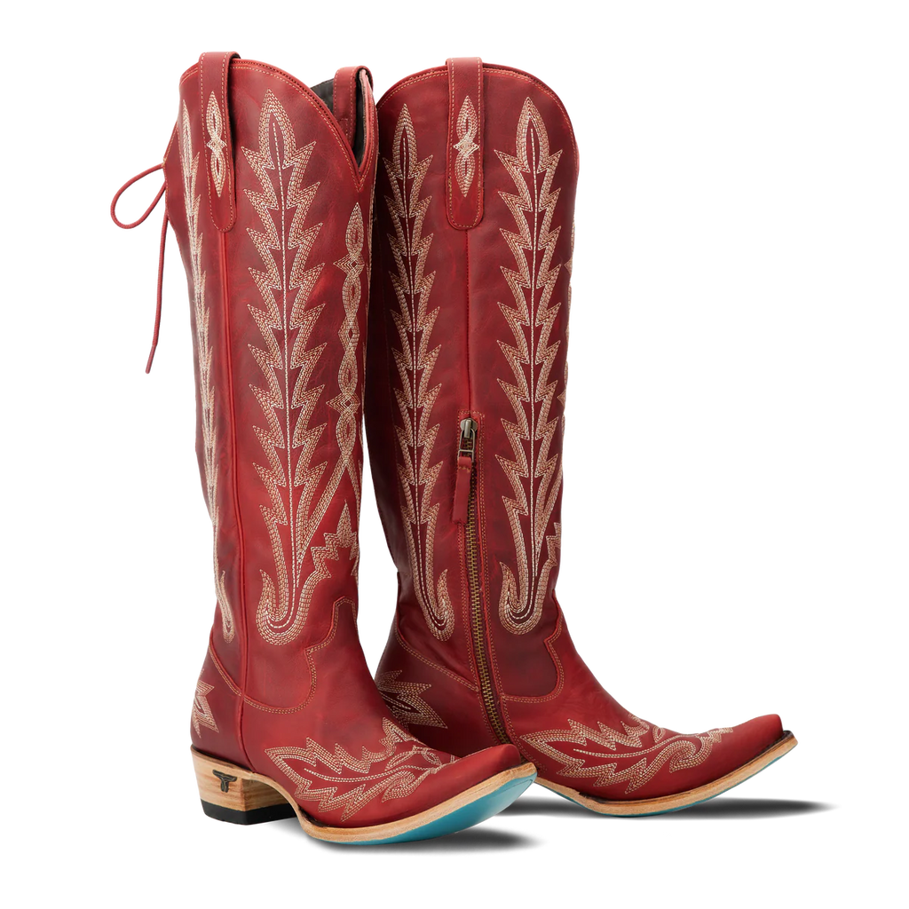 Red cowboy boots with intricate white embroidery on a white background